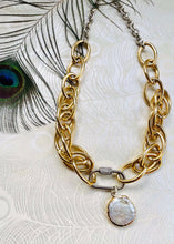 Load image into Gallery viewer, freshwater round Keshi Pearl set in a gold plated bezel pendant with handmade mixed metal statement chain necklace with micro pave' cubic zircons on a  carabiner locking clasp & white gold plating. sitting on peacock patterned pearl paper with peacock feather in left corner