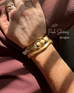 Beige coloured gemstones & gold shell bead with gold textured tube bead bracelet & gold bangles on hand with brown pants 