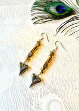 Load image into Gallery viewer, Silver heart earrings with gold and hematite beads next to a peacock feather 