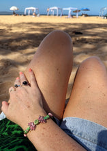 Load image into Gallery viewer, Pink &amp; green ceramic palm tree beaded bracelet on wrist of figure with beach in front