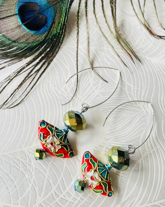olive green crystal earrings with red enamel Cloisonné fan shaped bead & sterling silver textured ear hooks on a beige background with a peacock feather