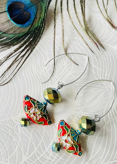 olive green crystal earrings with red enamel Cloisonné fan shaped bead & sterling silver textured ear hooks on a beige background with a peacock feather