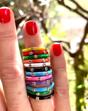 Load image into Gallery viewer, a range of 12 different coloured enamel stacking rings worn on a finger with red nail polish