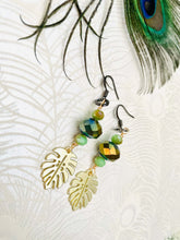 Load image into Gallery viewer, Gold-metal-monstera-leaf-with-olive-green-Czech-crystal-beads-gunmetal-ear-hooks-with-peacock-feather