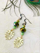 Load image into Gallery viewer, Gold-metal-monstera-leaf-with-olive-green-Czech-crystal-beads-gunmetal-ear-hooks-with-peacock-feather