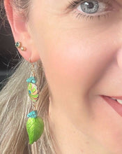 Load image into Gallery viewer, Iridescent Green leaf &amp; round enamel cloissone flower design earrings including turquoise stones &amp; 14ct gold filed ear hooks worn on a model with blonde hair &amp; blue eyes