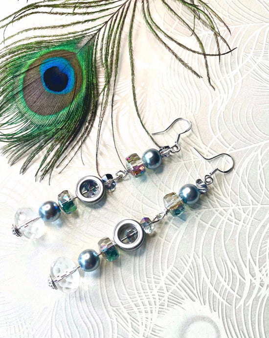 Faceted clear Czech crystal with blue toned Swarovski pearl & hematite earrings with sterling silver hooks on peacock pattern background with feather
