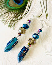 Load image into Gallery viewer, Iridescent blue raw quartz pointed stone earrings with Smokey quartz brown toned Swarovski crystal &amp; sterling silver ear hooks on peacock feather patterned background