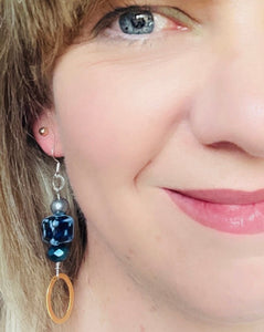 Cobalt blue cube ceramic bead earrings with Swarovski & Czech crystal, a gold toned oval feature & sterling silver ear hooks on blonde hair blu eye model