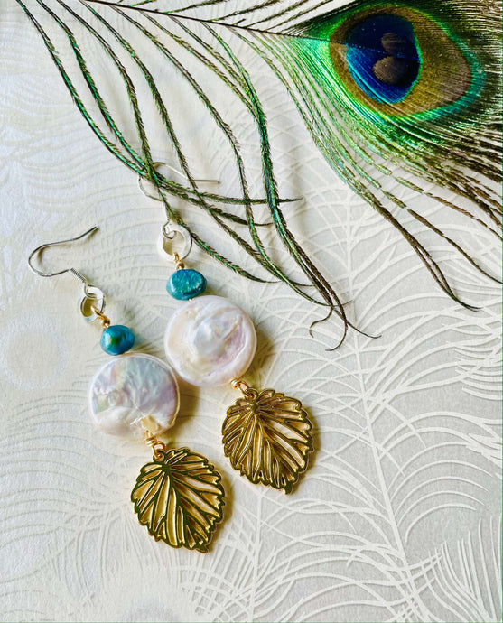 gold-leaf-charm-with-white-20mm-keshi-coin-pearl-turquoisr freshwater -pearl-hanging-from-silver-ear-hook-next-to-peacock-feather