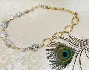 mixed shape white keshi pearl necklace with gold and silver chain next to peacock feather 