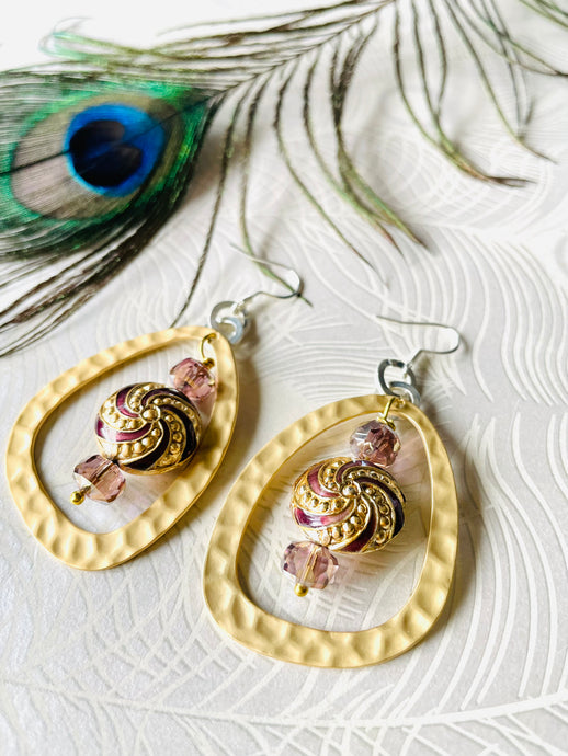 Purple & Gold round enamel Cloisonné Bead earrings including gold plated hammered finish loop with crystals & sterling silver ear hooks sitting on paper with a peacock feather in the background