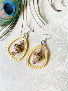 Purple & Gold round enamel Cloisonné Bead earrings including gold plated hammered finish loop with crystals & sterling silver ear hooks sitting on paper with a peacock feather in the background