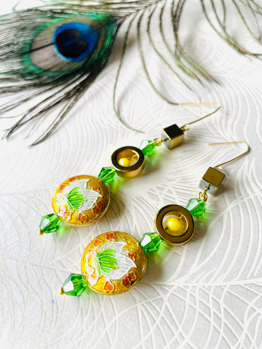 Green & yellow round enamel cloissone flower design earrings including gold hematite & Swarovski crystals & 14ct gold filled ear hooks on white background with peacock feather