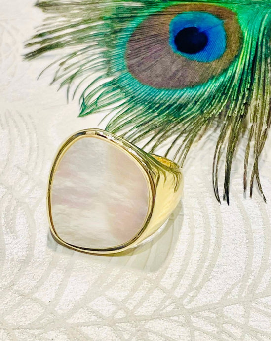 Gold ring with round square shape mother of pearl inlay on peacock feather patterned background 