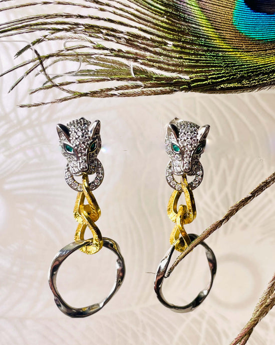 Sterling Silver plated pave crystal panther head with green crystal eyes and two toned gold & silver metal loops on white background with peacock feather