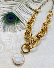 Load image into Gallery viewer, freshwater round Keshi Pearl set in a gold plated bezel pendant with handmade mixed metal statement chain necklace with micro pave&#39; cubic zircons on a  round carabiner locking clasp &amp; gold plating. sitting on peacock patterned pearl paper with peacock feather in left corner