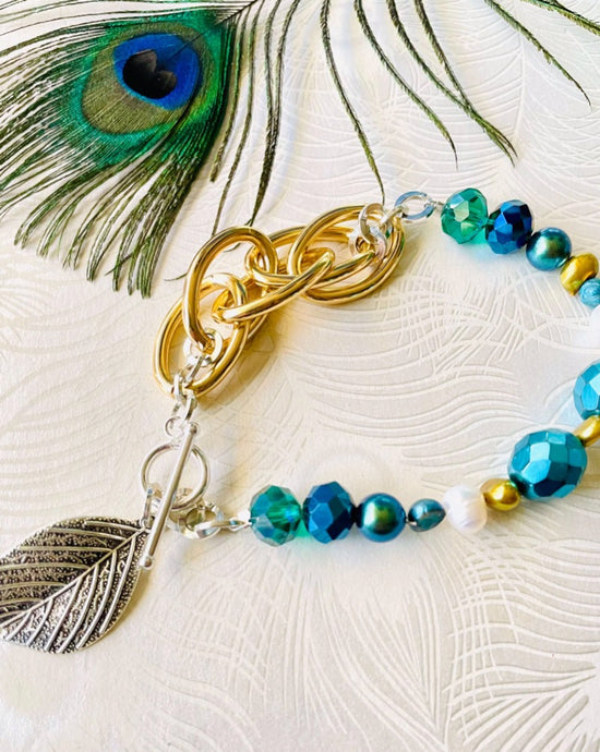 Silver leaf hanging off sterling silver toggle clasp with turquoise & blue crystal & gold chain bracelet